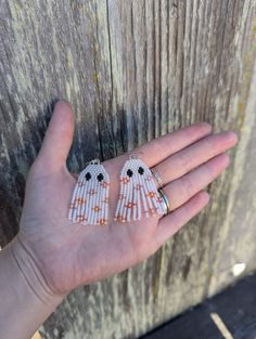 a person's hand holding two small white beaded earrings on top of each other