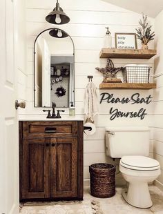 a white toilet sitting next to a wooden sink vanity in a bathroom under a mirror