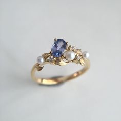 a gold ring with an oval blue sapphire surrounded by pearls