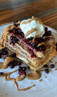 a white plate topped with pancakes covered in syrup and whipped cream