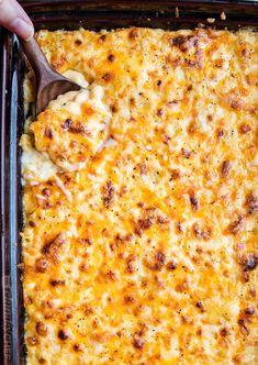 a casserole dish with cheese being scooped from it