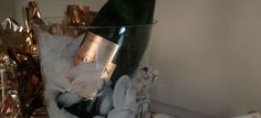 a glass filled with champagne and ice on top of a counter next to a bottle