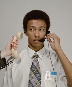 a man holding a telephone to his ear while another person holds an object in front of him