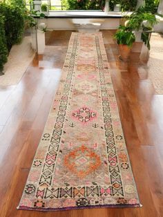 a long rug is on the floor in front of some potted plants and windows