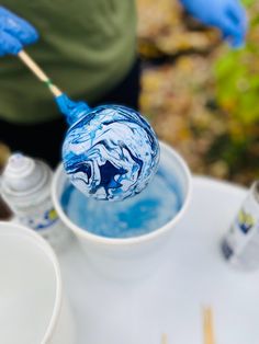 a person holding a toothbrush in a cup filled with blue liquid