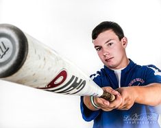 a young man holding a baseball bat in his right hand and looking at the camera