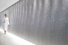 a woman standing in front of a wall with silver sequins on the walls