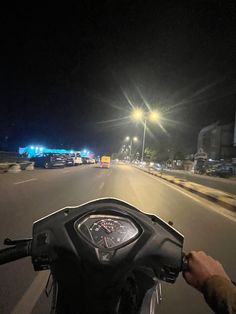 a person on a motor bike driving down the street at night with traffic behind them