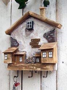 a wooden house with a bicycle on the roof and key hooks hanging from it's side