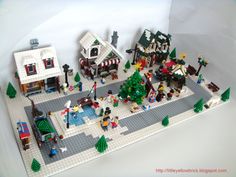 a lego model of a town with people and trees in the front, on a white background