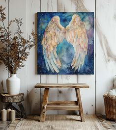 an angel wings painting hanging on the wall next to a bench and potted plant