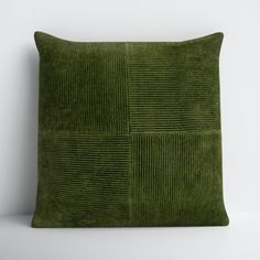 a green velvet pillow sitting on top of a white wall