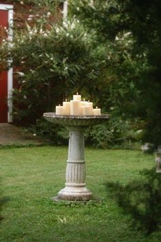 candles are lit on a pedestal in the yard