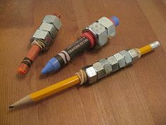 three different colored pencils sitting next to each other on a wooden table with two erasers