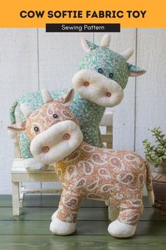 two stuffed cows sitting on top of a wooden bench next to each other with the words cow