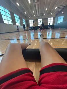 the legs and feet of a person on a basketball court with people in the background