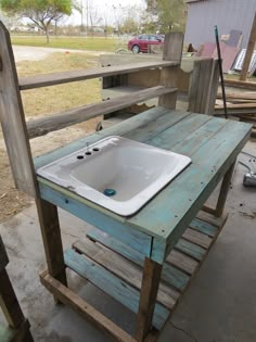 a sink sitting on top of a wooden table in front of a fenced area