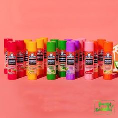 many different colors of toothpaste on a pink background