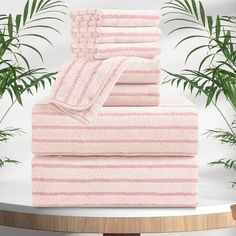 three towels stacked on top of each other in front of a potted palm tree