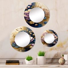 three circular mirrors are hanging on the wall above a table with vases and books