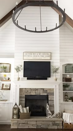 the living room is decorated in white and has a large television on top of the fireplace