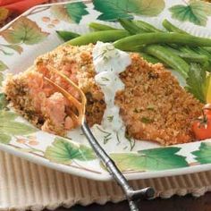 a white plate topped with meat and veggies next to a fork on a table