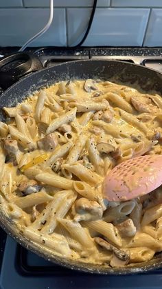 a skillet filled with pasta and mushrooms on top of a stove