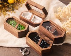 three wooden boxes with wedding rings in them on a table next to flowers and other accessories