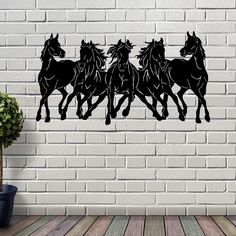 three horses running in the same direction on a brick wall with a potted plant next to it