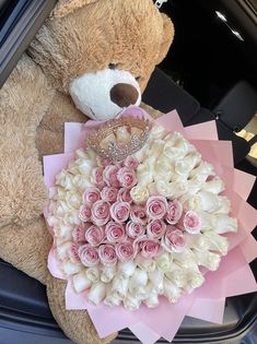 a teddy bear sitting in the back seat of a car holding a bouquet of roses