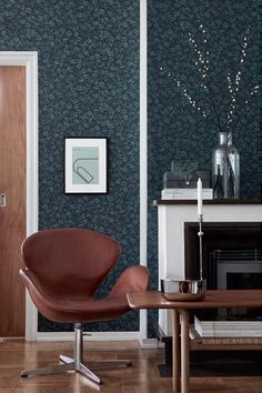 a chair and table in a room with blue wallpaper on the walls next to a fireplace