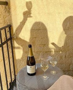 a bottle of wine sitting on top of a table next to two glasses of wine