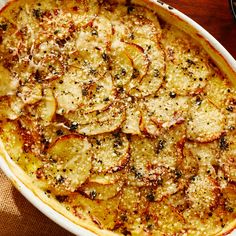 a casserole dish with potatoes and herbs in it sitting on a table top