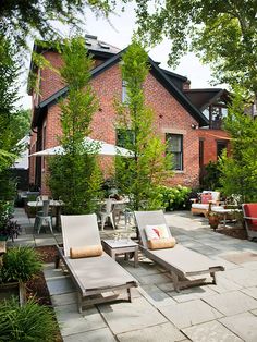 an outdoor patio with lounge chairs and trees