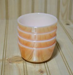 four orange and white cups sitting on top of a wooden table next to each other