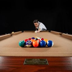 a man leaning over a pool table with eight balls in front of him and an award plaque