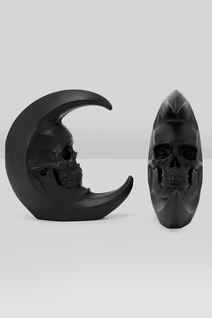 a skull sitting on top of a crescent next to a black object with a half moon