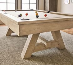 a pool table with balls on it in front of a window and carpeted floor