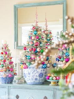 a decorated christmas tree sitting on top of a blue dresser in front of a mirror