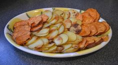 a white plate topped with sliced potatoes on top of a table