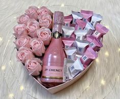 a heart shaped box filled with lots of pink roses and a bottle of ginet