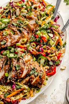 a white plate topped with chicken and veggies next to a fork on a table