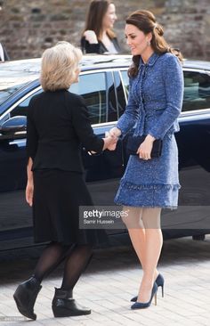 two women shaking hands in front of a car