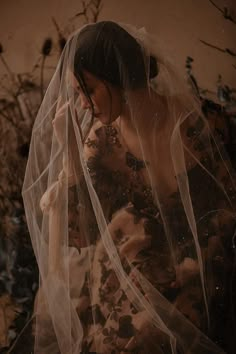 a woman with a veil on her head is standing in front of some plants and flowers