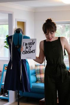 a woman standing in front of a mannequin holding a sign that says i made my clothes