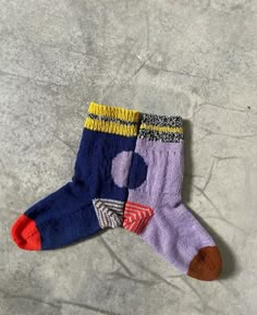 two pairs of colorful socks sitting on top of a cement floor next to each other