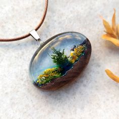 a glass pendant with plants in it sitting on a table next to some yellow flowers