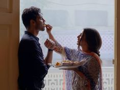 a man and woman are eating food out of their mouths while standing in front of a door