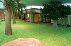 an indoor area with artificial grass and palm trees