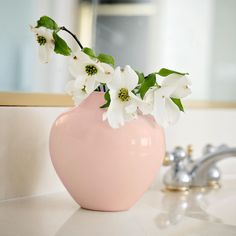 a pink vase filled with white flowers sitting on top of a bathroom counter next to a faucet